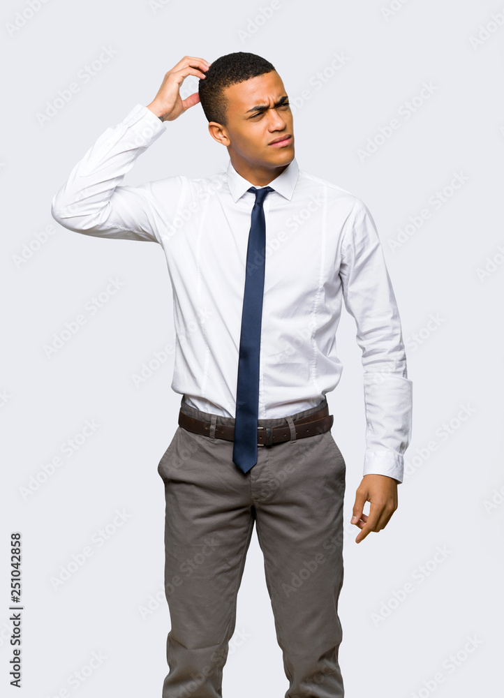 Young afro american businessman having doubts while scratching head on isolated background Young afro american businessman having doubts while scratching head on isolated background