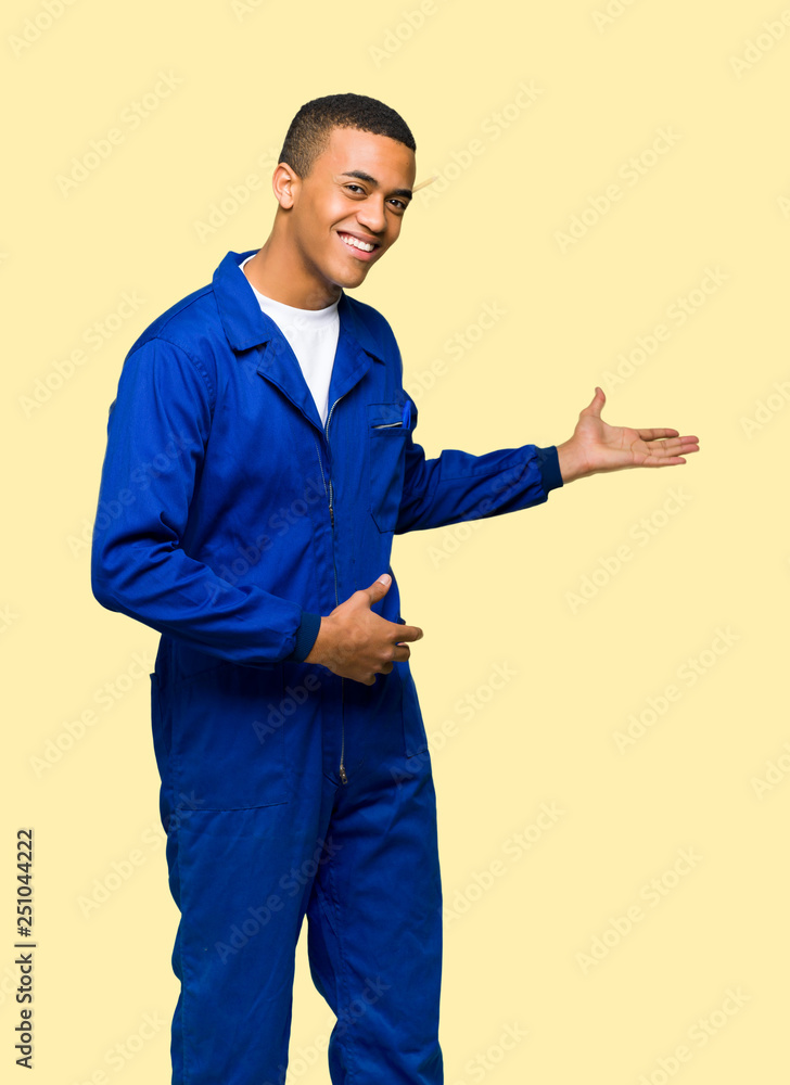 Young afro american worker man pointing back and presenting a product on isolated background Young afro american worker man pointing back and presenting a product on isolated background