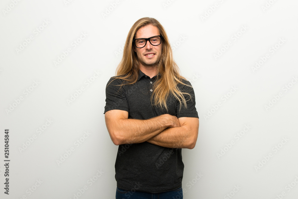 Blond man with long hair over white wall with glasses and happy Stock
