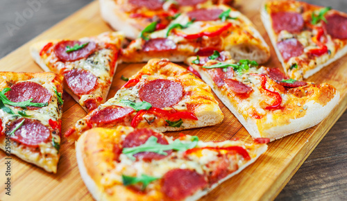 Pepperoni Pizza with Mozzarella cheese, salami, Tomatoes, pepper, Spices and Fresh arugula. Italian pizza on wooden table background