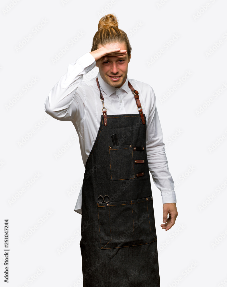 Barber man in an apron looking far away with hand to look something on isolated background Barber man in an apron looking far away with hand to look something on isolated background