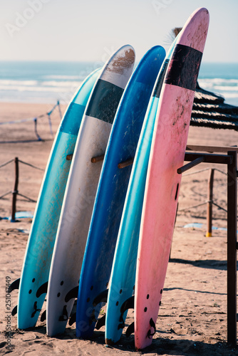 Different colors of surf on a the sandy beach in Casablanca - Morocco. Beautiful view on sandy beach and ocean. Surf boards for renting. Surfer school.