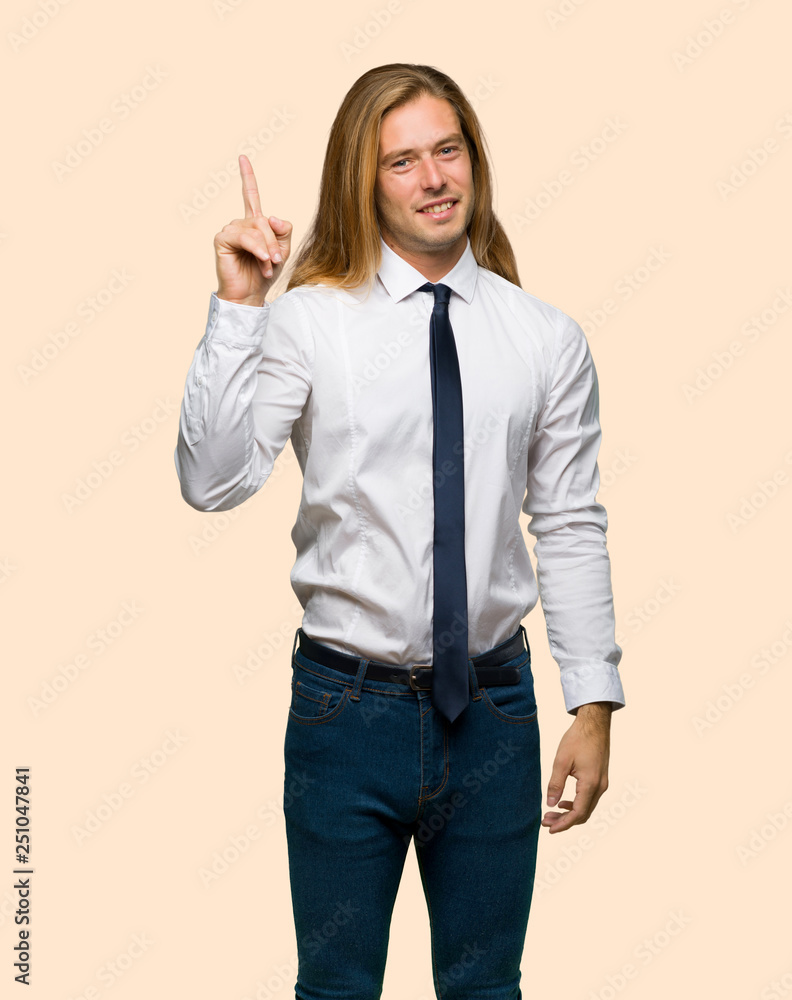 Blond businessman with long hair showing and lifting a finger in sign of the best on isolated background Blond businessman with long hair showing and lifting a finger in sign of the best on isolated background