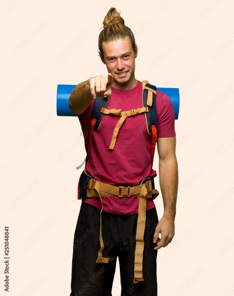Hiker man with mountain backpacker points finger at you with a confident expression on isolated background Hiker man with mountain backpacker points finger at you with a confident expression on isolated background