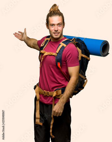 Hiker man with mountain backpacker pointing back and presenting a product on isolated background