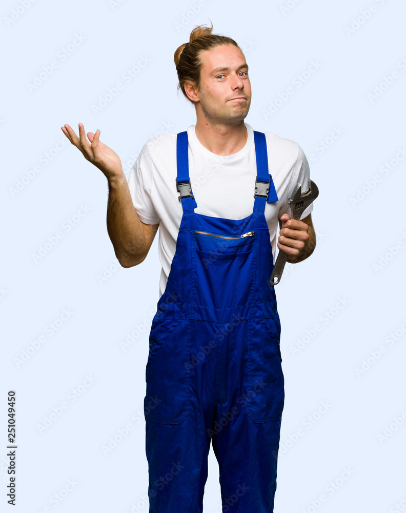 Workman having doubts while raising hands and shoulders on isolated background Workman having doubts while raising hands and shoulders on isolated background