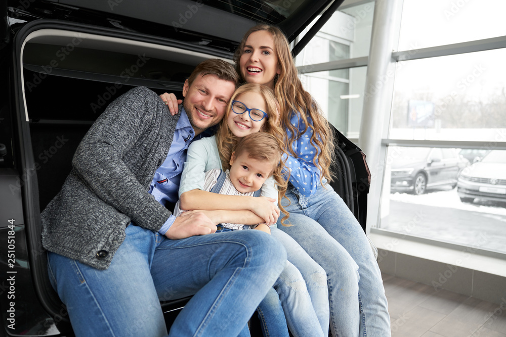 Cheerful family posing in car trunk of automobile. Cheerful family posing in car trunk of automobile.