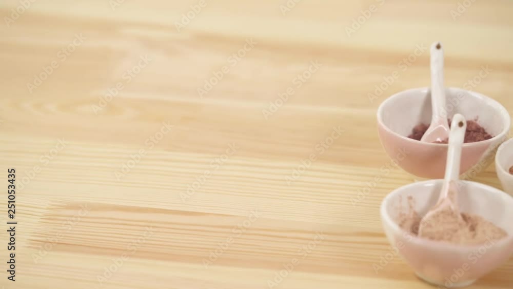 Top view of a ceramic bowls with spoons with different powders on a wooden table.