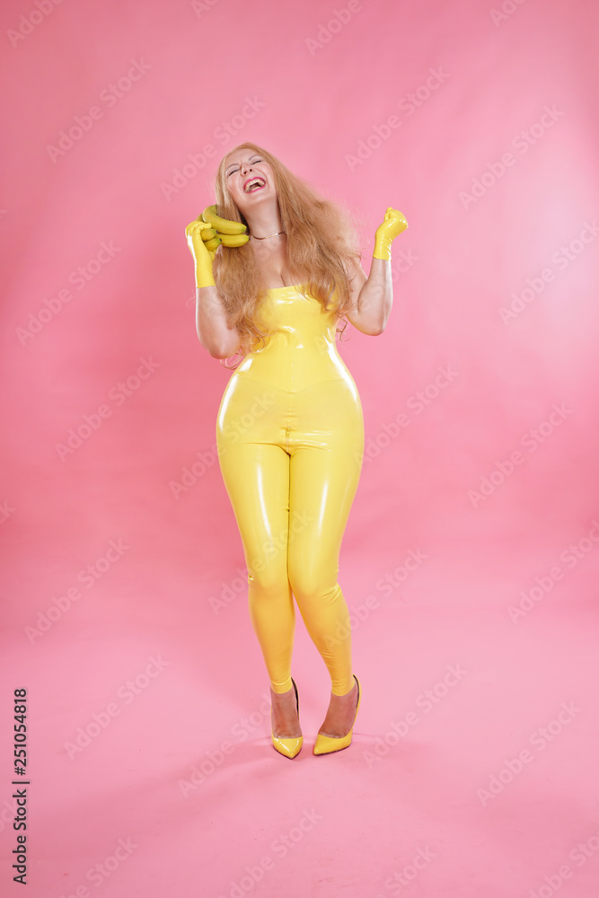 cute chubby blonde girl posing in yellow latex rubber clothes with sweet  bananas Photos | Adobe Stock