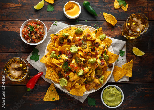 Foto Mexican nachos tortilla chips with olives, jalapeno, guacamole, tomatoes salsa, cheese dipand beer