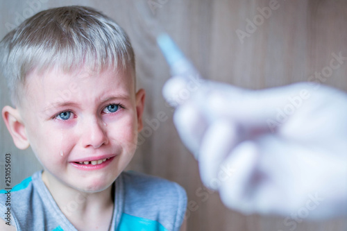 Baby boy is afraid of injections. He cries. Hand with syringe for injection. Vaccination against influenza and virus. Insulin syringe with thin needle. The child is afraid of injections.