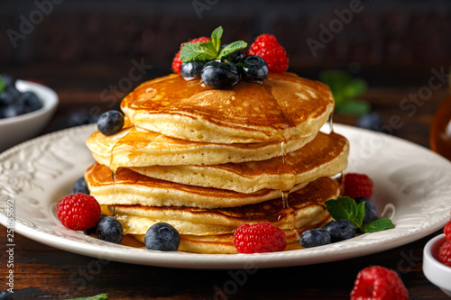 Homemade american pancakes with fresh blueberry, raspberries and honey. Healthy morning breakfast. rustic style photo