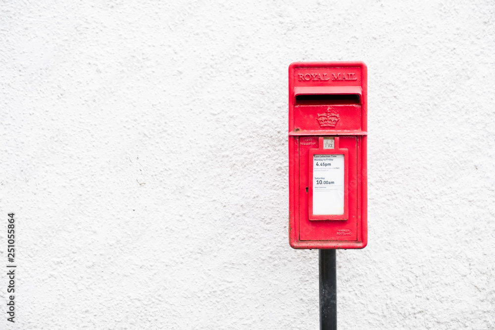 Red post mail box against plain white wall background Red post mail box against plain white wall background