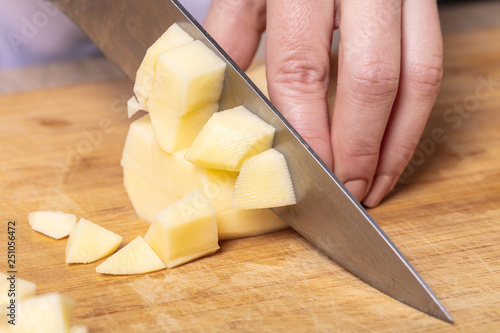 cook cuts potatoes on a wooden board