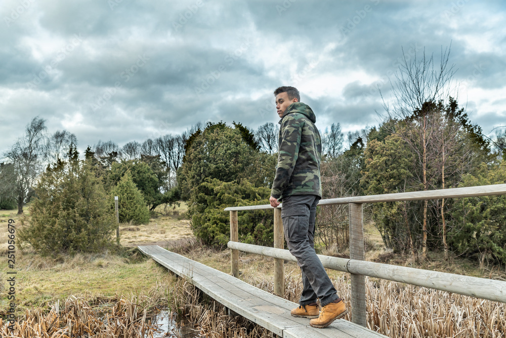 A young guy are hiking in a nature reserve in Sweden and goes over a creek in outdoor clothing A young guy are hiking in a nature reserve in Sweden and goes over a creek in outdoor clothing