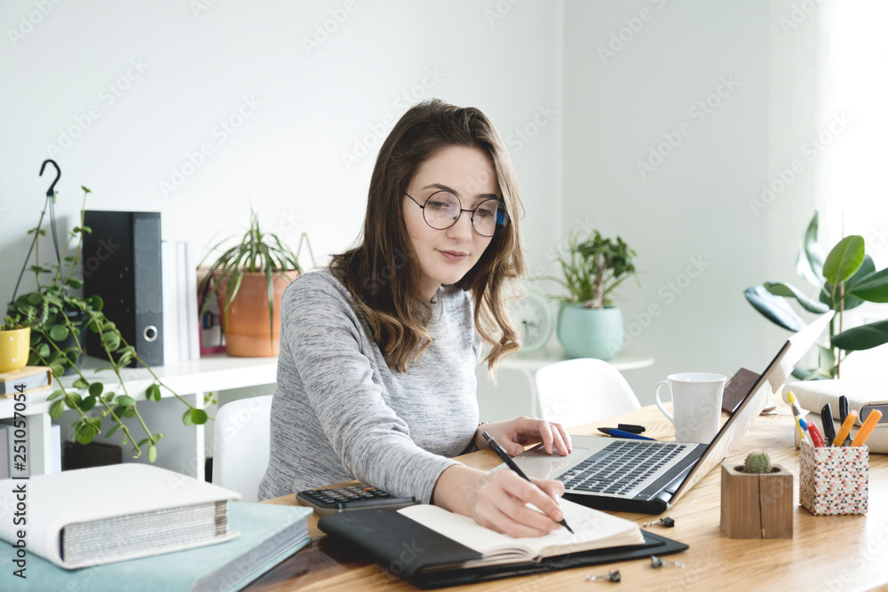 Young business woman taking notes in notebook at office.