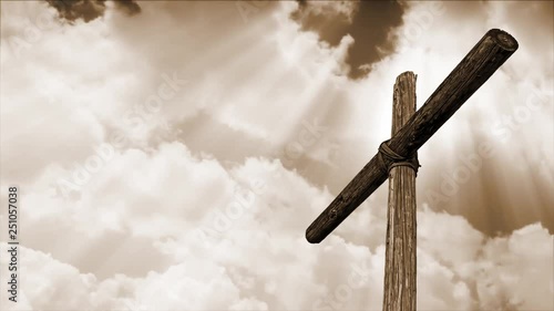 Looping time lapse motion clouds with an old rugged wooden cross in sepia tone and shining rays of sunlight. 
