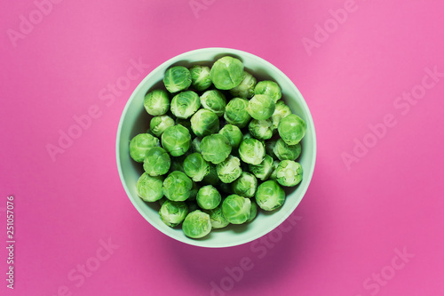 Fresh uncooked brussel sprouts in a bowl on pink background. Photo with blank free space.