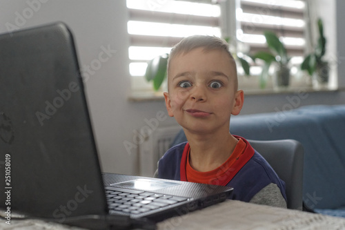 mały chłopak jest zadowolony używa laptopa 