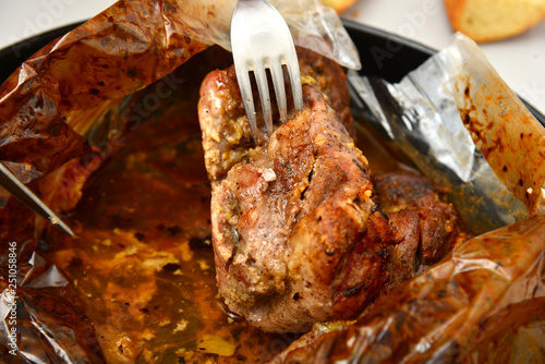 Roasted meat baked in the oven, knife and fork cutting roast.