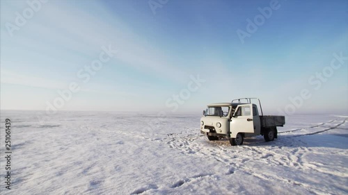 KHANKA DISTRICT, RUSSIA - MARCH 22, 2018: Sliding view of russian car UAZ 3303 standing on ice of frozen lake. Bright winter day, sunny weather photo