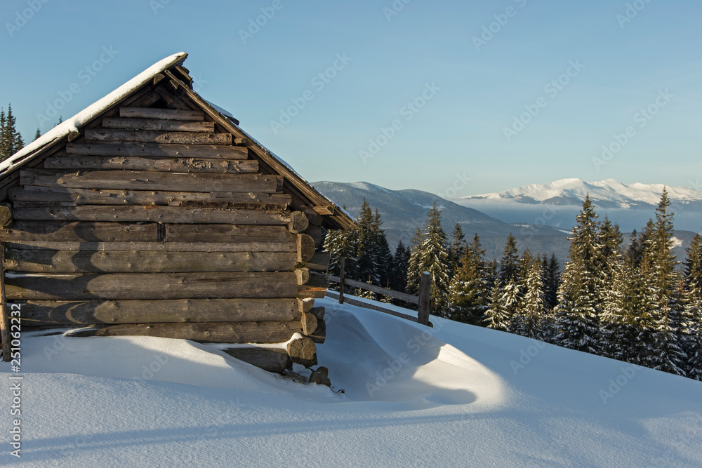 abandoned wooden hut in winter Carpathian mountains. shepherds' huts in the winter Carpathians on the background of snow-covered mountain ridges and coniferous forest. 