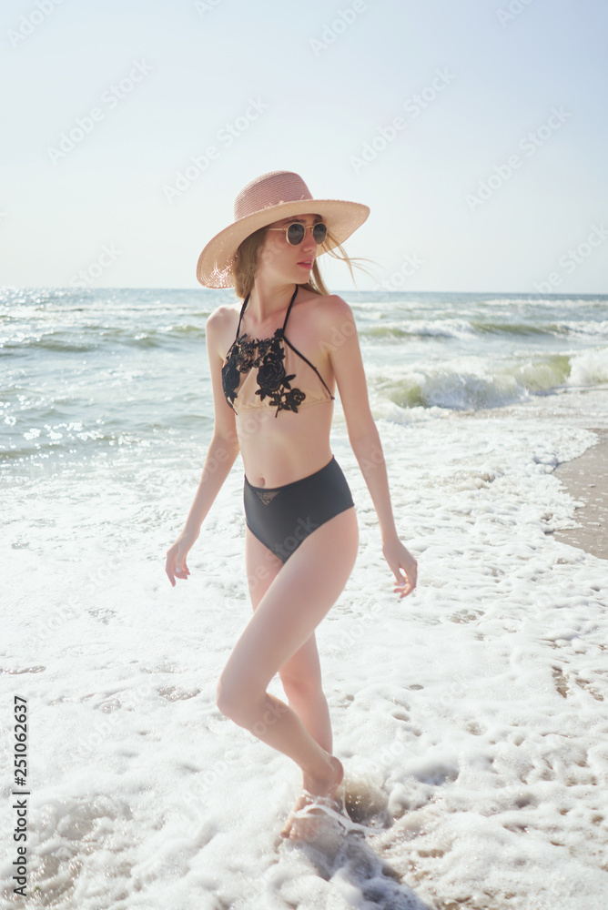 Girl enjoys relaxing near ocean. Concept travel, vacation. Model in swimsuit sunbathes on sand beach Girl enjoys relaxing near ocean. Concept travel, vacation. Model in swimsuit sunbathes on sand beach