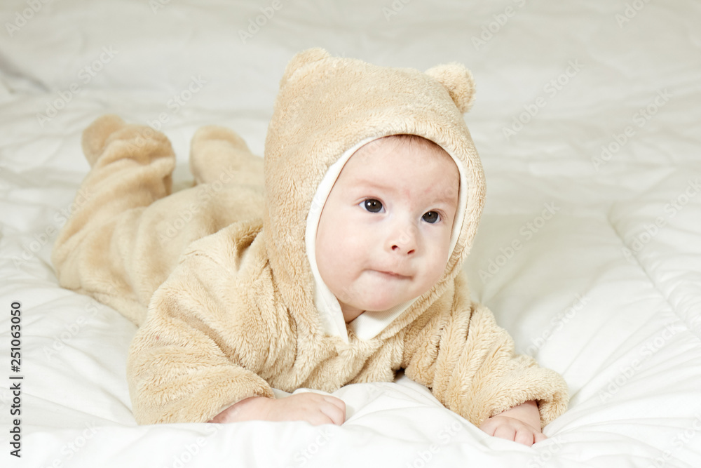 Little baby in a suit on a white bedspread Little baby in a suit on a white bedspread