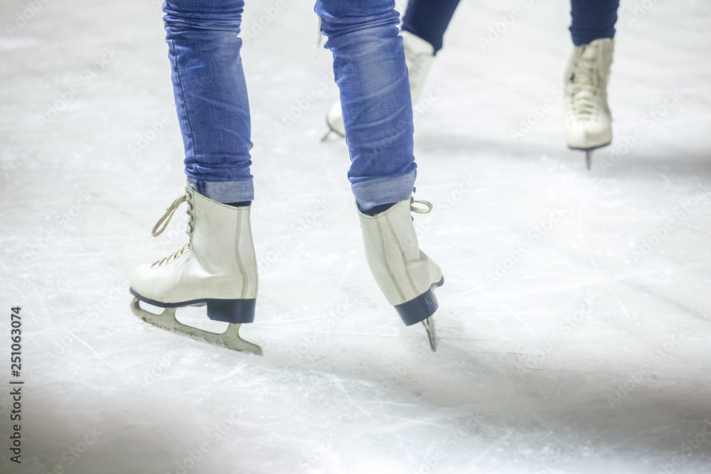 feet on the skates of a person rolling on the ice rink feet on the skates of a person rolling on the ice rink