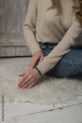 the girl is sitting on a white fur carpet, jade bracelet on the hand of the girl