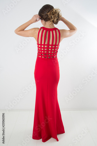 Rear View Of Sensual Woman With Elegant Hairstyle Posing In Red Evening Dress,Full-Length Studio Shot Against White Background