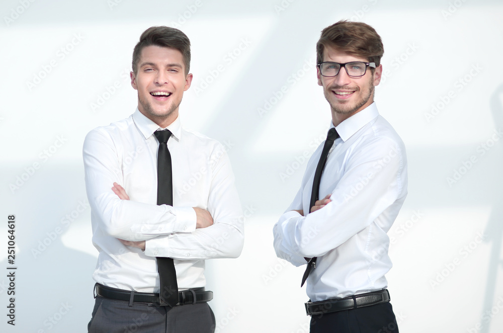 two businessmen stand with arms crossed and smile