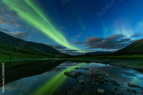 aurora borealis in the night sky cut the mountains, reflected in the water