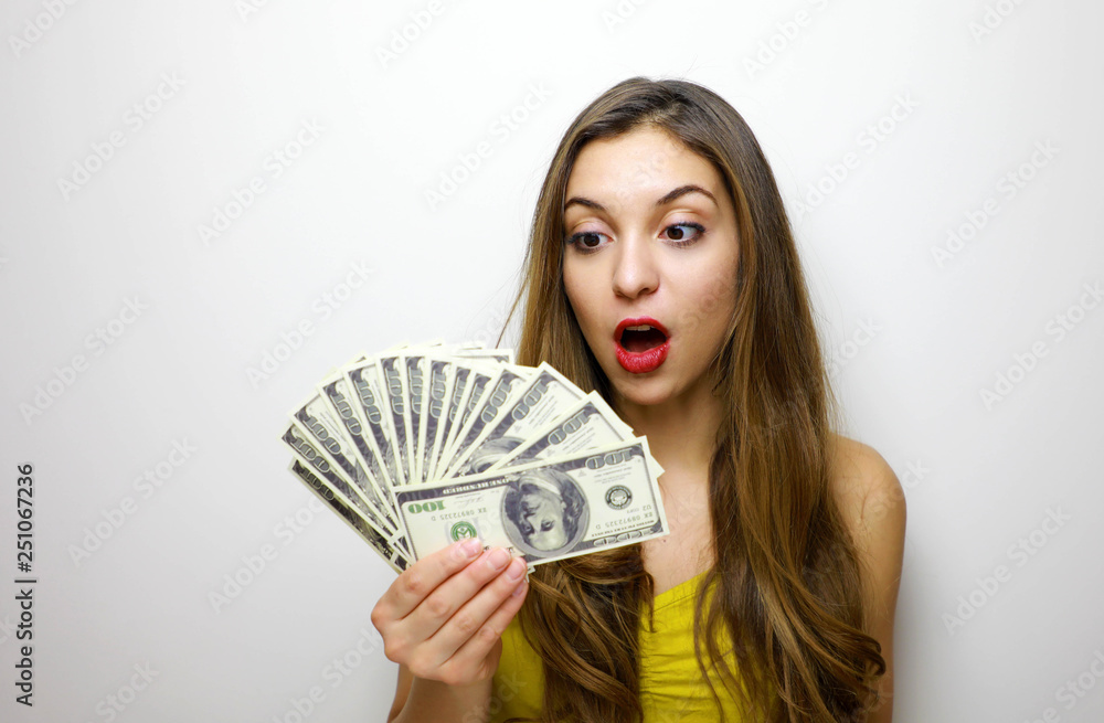 Portrait of a cheerful pretty girl looking at bunch of money banknotes isolated over white background Portrait of a cheerful pretty girl looking at bunch of money banknotes isolated over white background