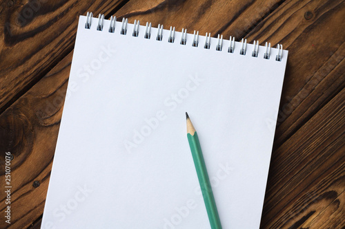 blank Notepad on wooden background and pencil