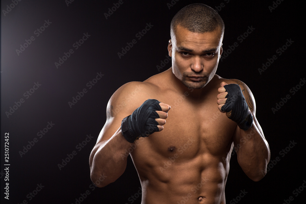 Muscular shirtless male fighter on black background