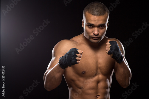 Muscular shirtless male fighter on black background