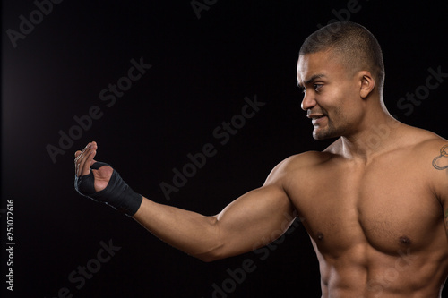 Muscular shirtless male fighter on black background