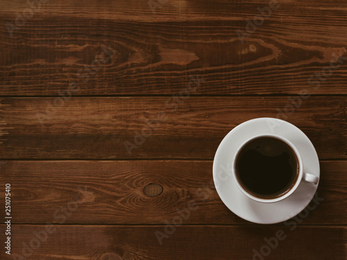 Cup of black coffee on a brown wooden background. Author processing, film effect, low key.
