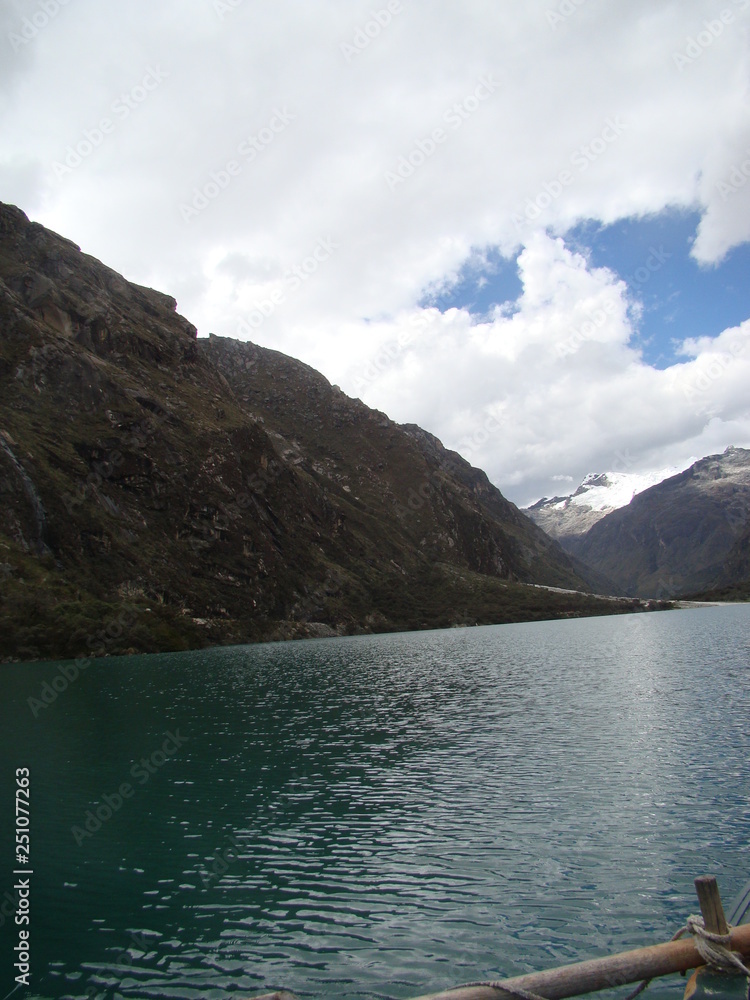 Mountain with snow on top and a turquoise lake below, blue sky with clouds Mountain with snow on top and a turquoise lake below, blue sky with clouds
