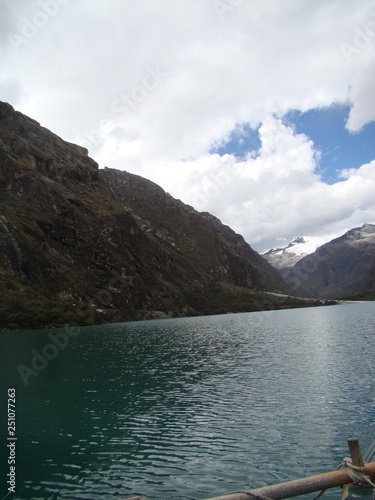 Mountain with snow on top and a turquoise lake below, blue sky with clouds