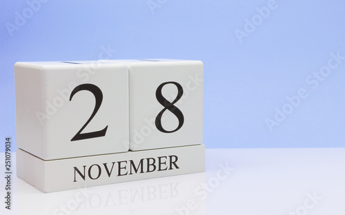 November 28st. Day 28 of month, daily calendar on white table with reflection, with light blue background. Autumn time, empty space for text photo