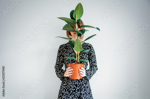 Beautiful woman in trendy dress with plant in a pot