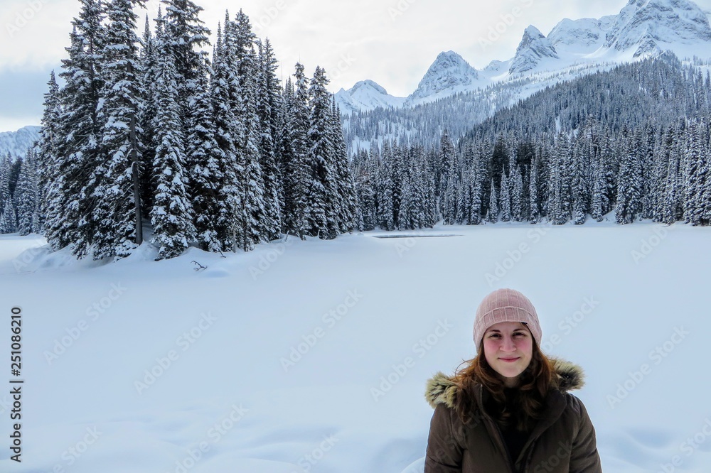 A young woman posing with the forests of Island Lake in Fernie, British Columbia, Canada behind. The majestic winter background is an absolutely beautiful place to go hiking with fresh fallen snow. A young woman posing with the forests of Island Lake in Fernie, British Columbia, Canada behind. The majestic winter background is an absolutely beautiful place to go hiking with fresh fallen snow.