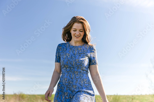 Happy woman with beautiful blonde hair smiling and running on the green meadow