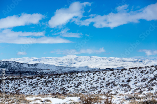 Snow covered desert landscape with puffy clouds and blue sky