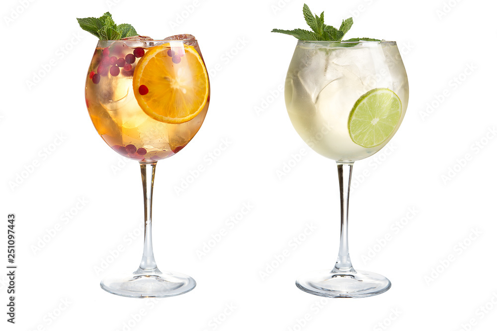 Two light alcoholic or non-alcoholic cocktails with mint, fruits and berries on a white background. Cocktails in glass goblets.