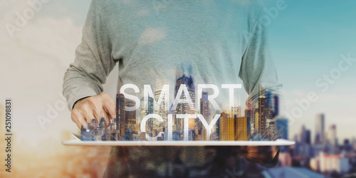Smart city technology, a man using digital tablet, and modern buildings hologram