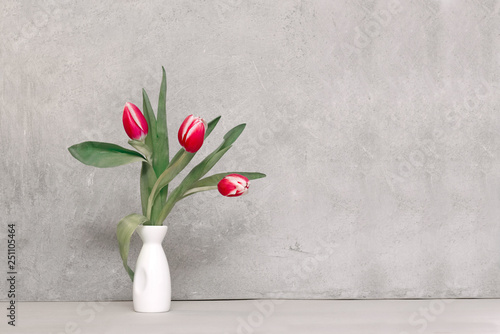 bouquet of tulips in a vase against a concrete wall