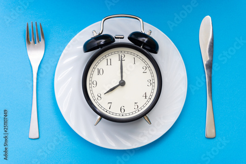 Alarm clock with fork and knife on the table. Time to eat, Breakfast, Lunch time and dinner concept.